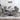 Dining room setup with a round table and four gray chairs in a well-lit room.